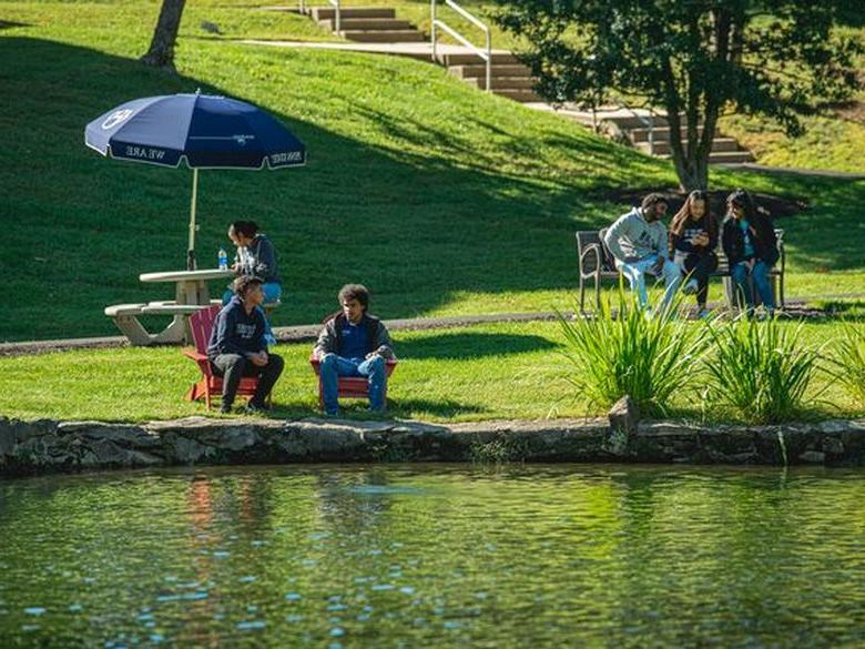 Students sit by the Lares Pond